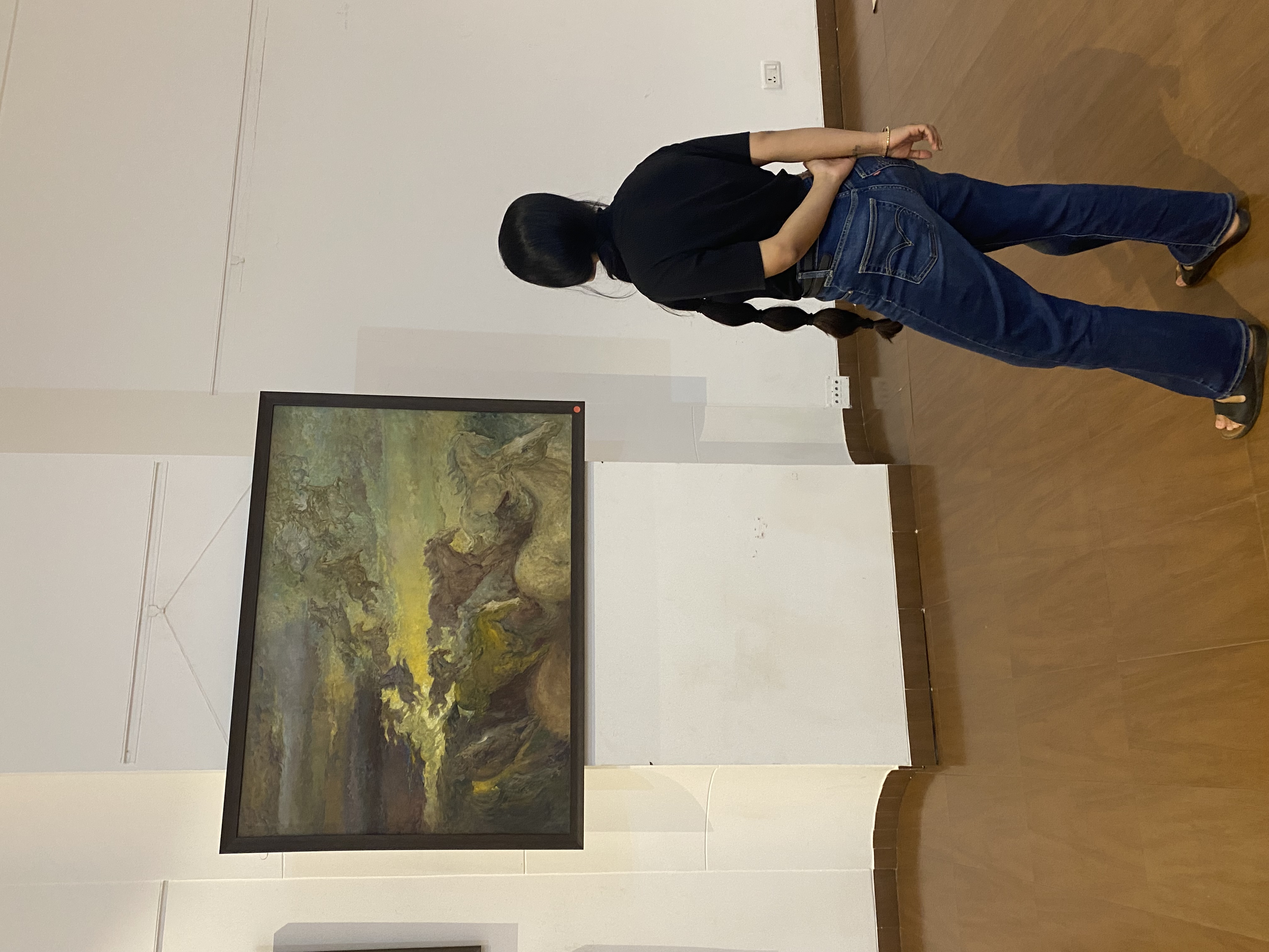 A visitor stands before Horses Fantasy, Late Shri Pratap Mulick’s large oil of horses surging through a storm-lit sky